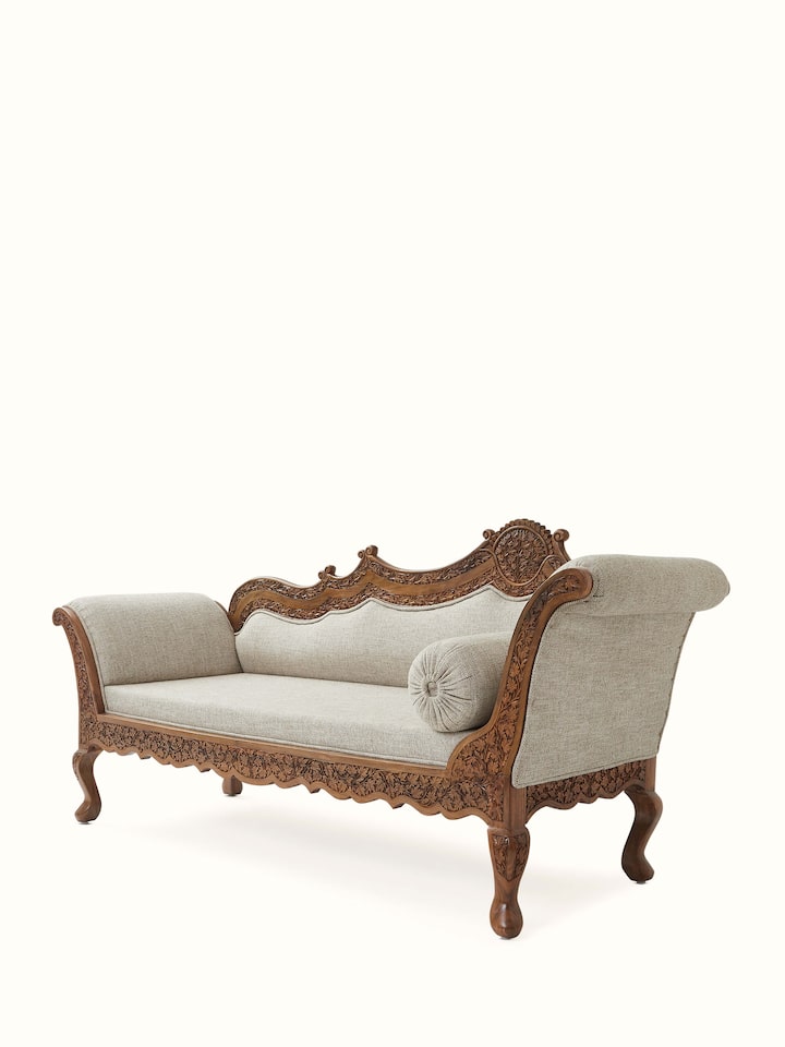 Close-up of the carved walnut wood legs of the handloom fabric upholstered daybed, emphasizing the intricate woodwork