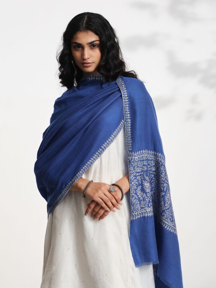 Angled view of blue Palledar Sozni embroidered shawl highlighting Sozni stitch technique