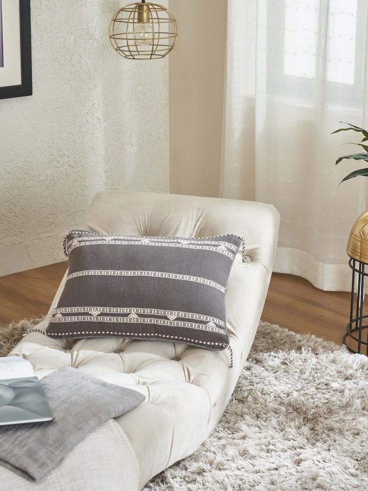 Lifestyle view of Anek Coffee Bhujodi Cushion Cover placed on a beige sofa setting
