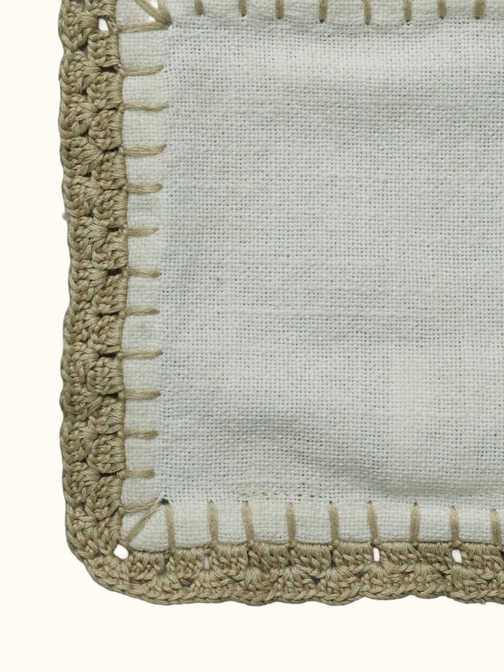 Detail view of Nityam Ivory Cotton Slub Crochet Coasters Set Of 6 highlighting the fabric texture and embroidery detail, from a different angle