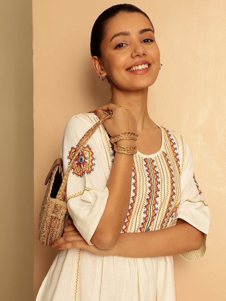 Angled view of off-white short cotton Rajasthani embroidered dress displaying intricate stitching and pattern on lightweight cotton fabric.