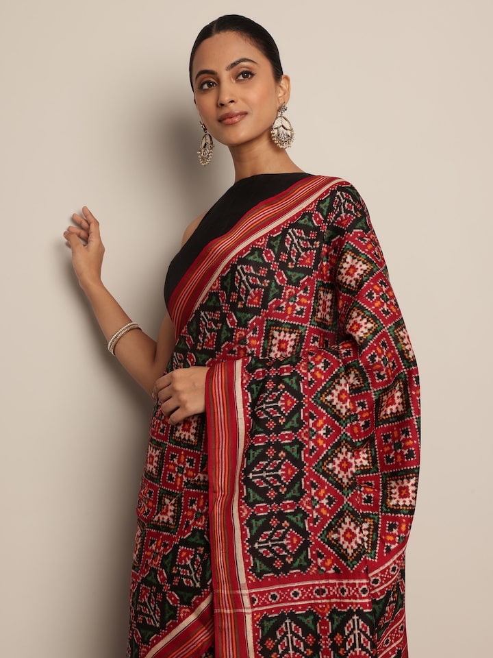 Angled view of Red & Green Mulberry Silk Patan Patola Saree highlighting intricate Patola weave and color contrast.