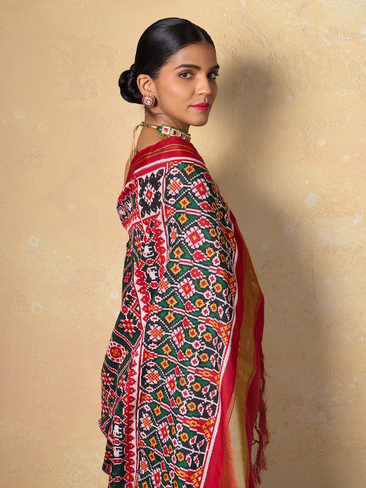 Red mulberry silk Patan Patola saree angled view emphasizing intricate double ikat weaving and rich texture