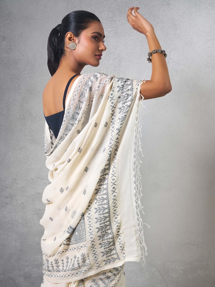Angled view of off-white cotton Jamdani saree showing border and pallu details.