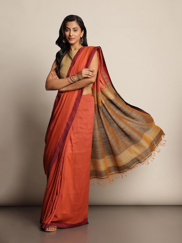 Lifestyle view of linen saree in grey styled with contrast blouse and accessories.