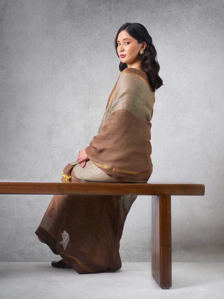 Angled view of beige linen cotton saree showing fabric drape and texture.