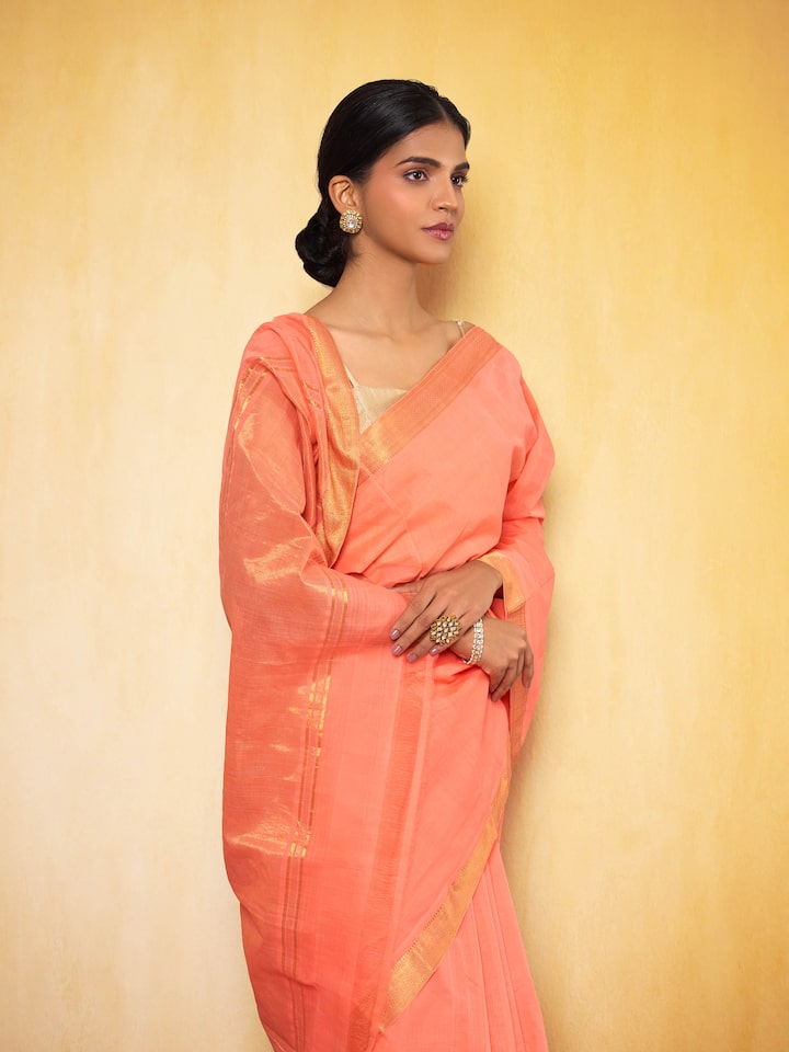 Angled view of peach cotton saree showing soft texture and border details.