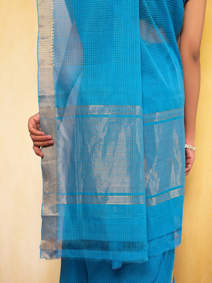 Detailed view of the saree drape displaying its fine cotton texture and gold zari detailing.