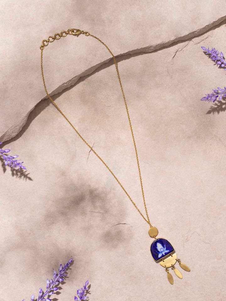Close-up of Blue pottery pendant showing detailed design and chain linkage.