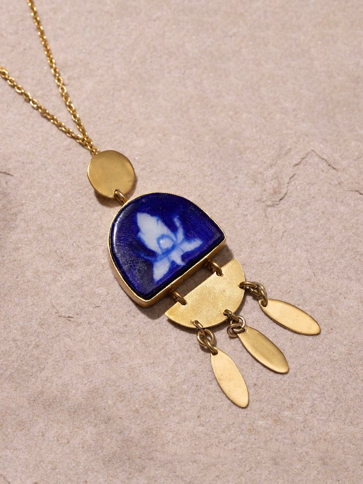 Blue pottery pendant and chain displayed on a flat surface, emphasizing its detailed design.