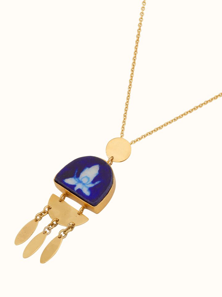 Blue pottery pendant and chain shown from an overhead view to highlight its full design.
