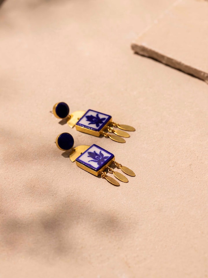 Detailed close-up of blue pottery drop earrings focusing on design and texture