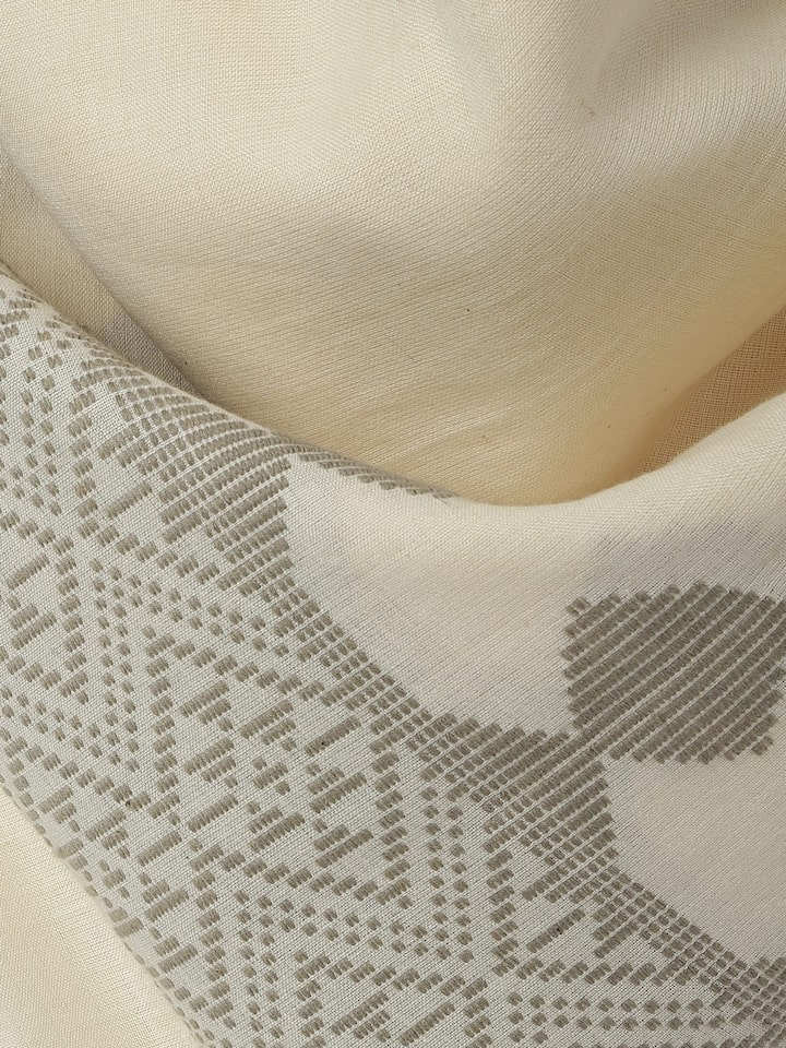 Close-up of extra-weft pattern on white cotton stole showcasing handloom texture.