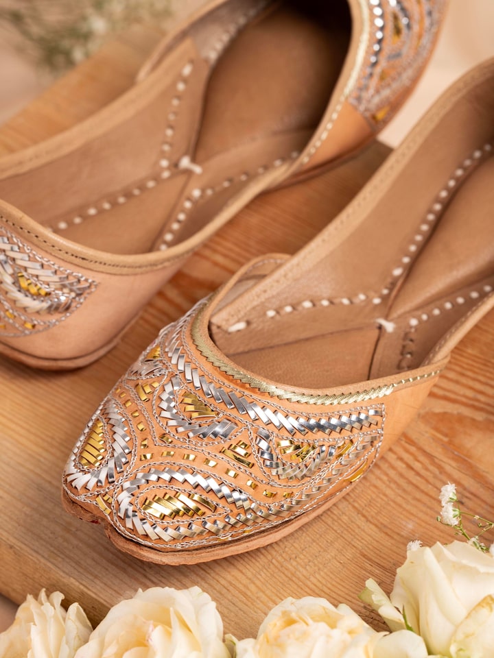 Close-up of Ecru Leather Haryana Juttis showing intricate embroidery and leather texture.