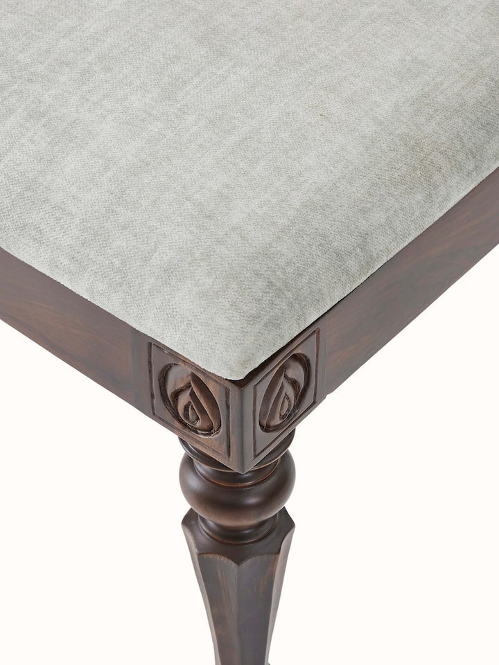 Detailed view of carved rosewood dining chair’s backrest, showcasing intricate carving patterns and upholstered detail.