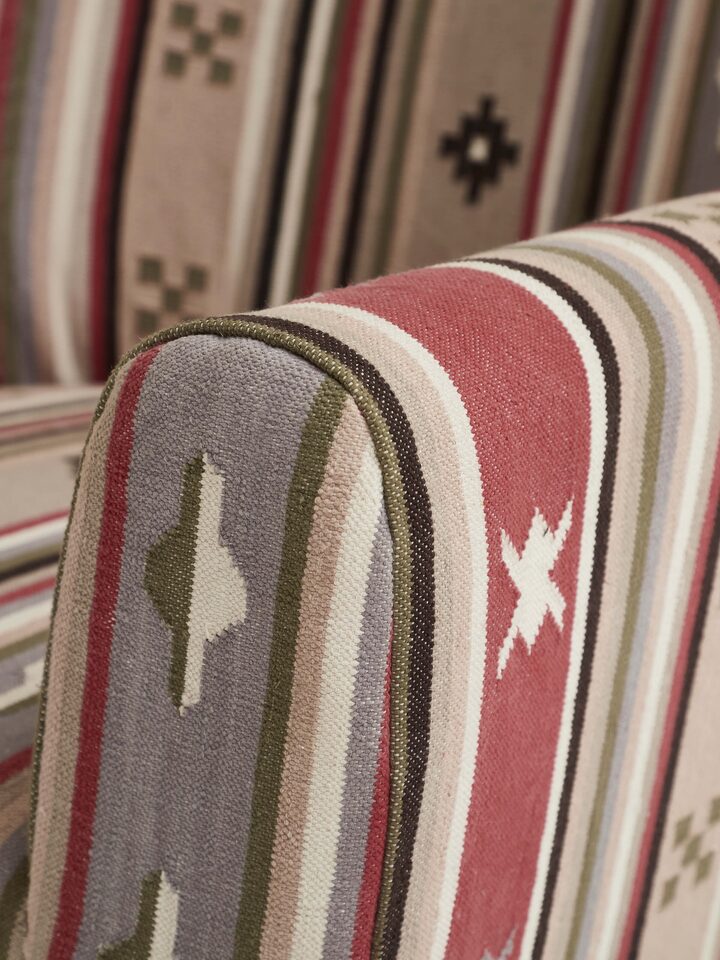 Angle view of Panja Dhurrie upholstered Sheesham wood wing chair, capturing the elegant design and upholstery