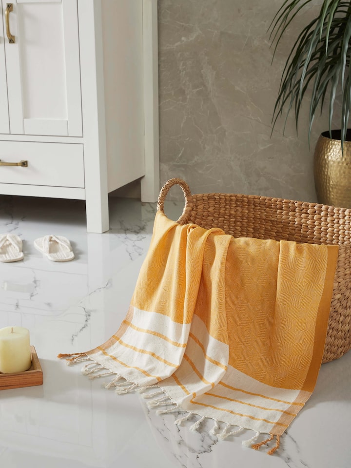Close-up view of a large yellow striped cotton bath towel, highlighting its bright color and striped pattern.