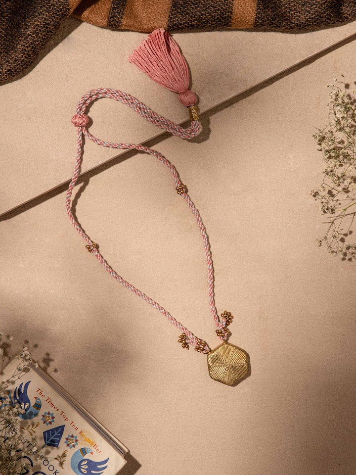 Close-up of Dhokra pendant and chain showing detailed metalwork and traditional motifs.