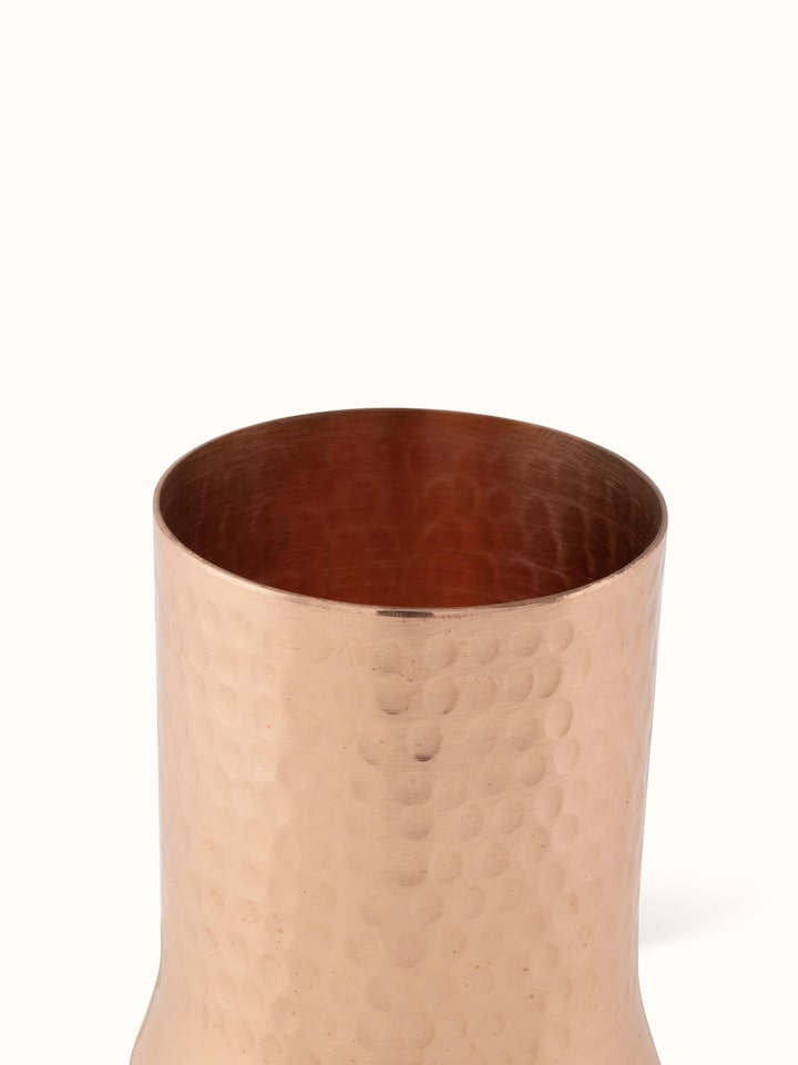 Detailed view of the base of copper metal glass, showcasing its sturdy build and polished finish.