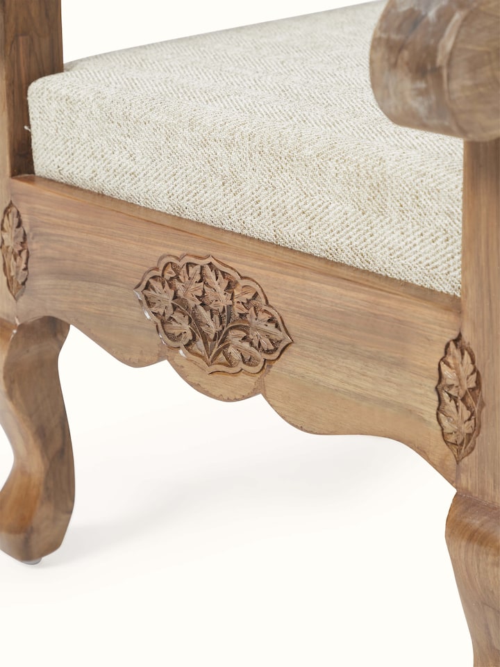 Detailed view of the carved walnut wood frame and handloom fabric upholstery of the armchair, emphasizing intricate woodwork and texture