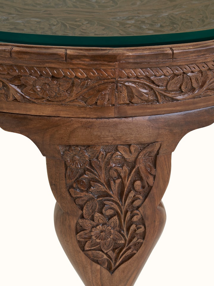 Detail view of Carved Walnut Wood Round Coffee Table with Glass Top highlighting the woodwork and finish detail