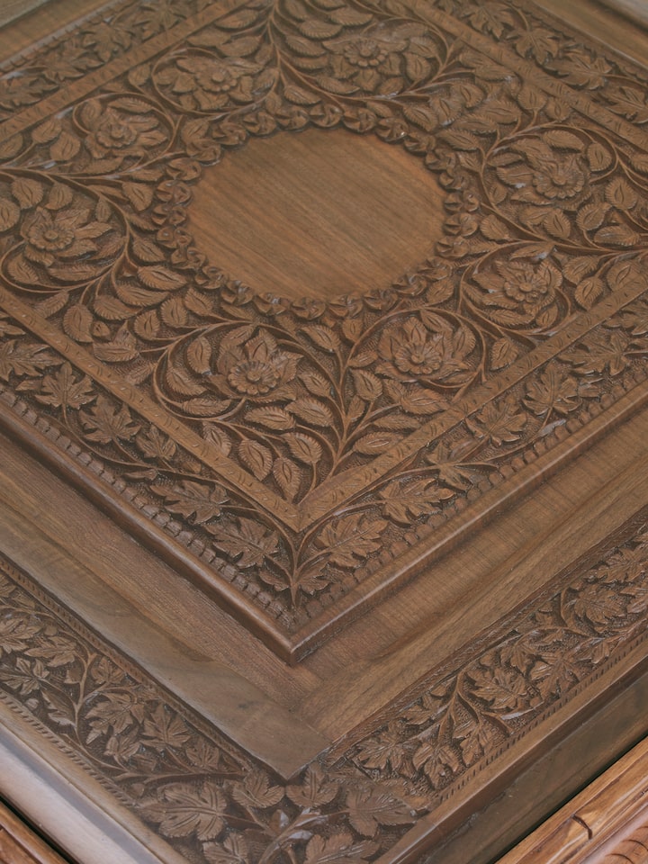 Detail view of Carved Walnut Wood Square Coffee Table with Glass Top highlighting the woodwork and finish detail, in an alternate close-up