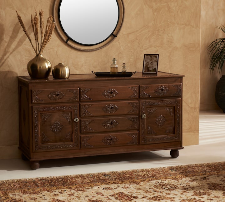 Side view of walnut wood sideboard, highlighting its natural finish and intricate carvings on the five drawers.