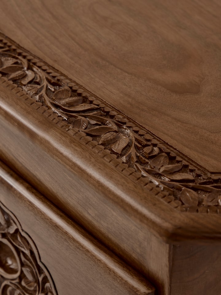Detailed view of the sideboard's carved surface and drawer handles, showcasing the fine craftsmanship