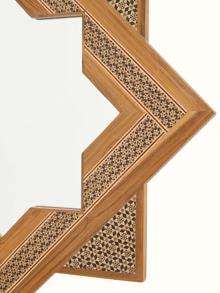 Detailed view of the star-shaped teak wood marquetry wall mirror from a different angle, showcasing the reflective surface and edges.