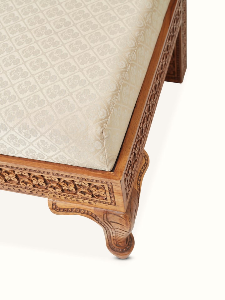 Close-up of the carved details on the Sheesham wood sofa, showing the intricate patterns and textures