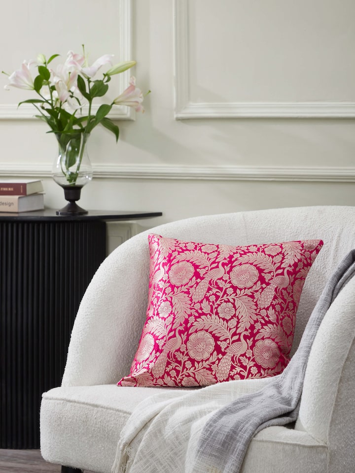Close-up of Avasa raspberry floral silk brocade Banarasi handloom cushion cover showing the intricate brocade work and floral design.