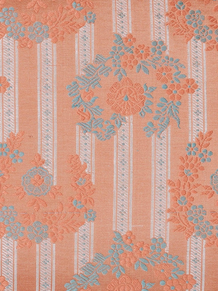 Angled detail shot capturing the rich Banarasi weave and peach silk texture