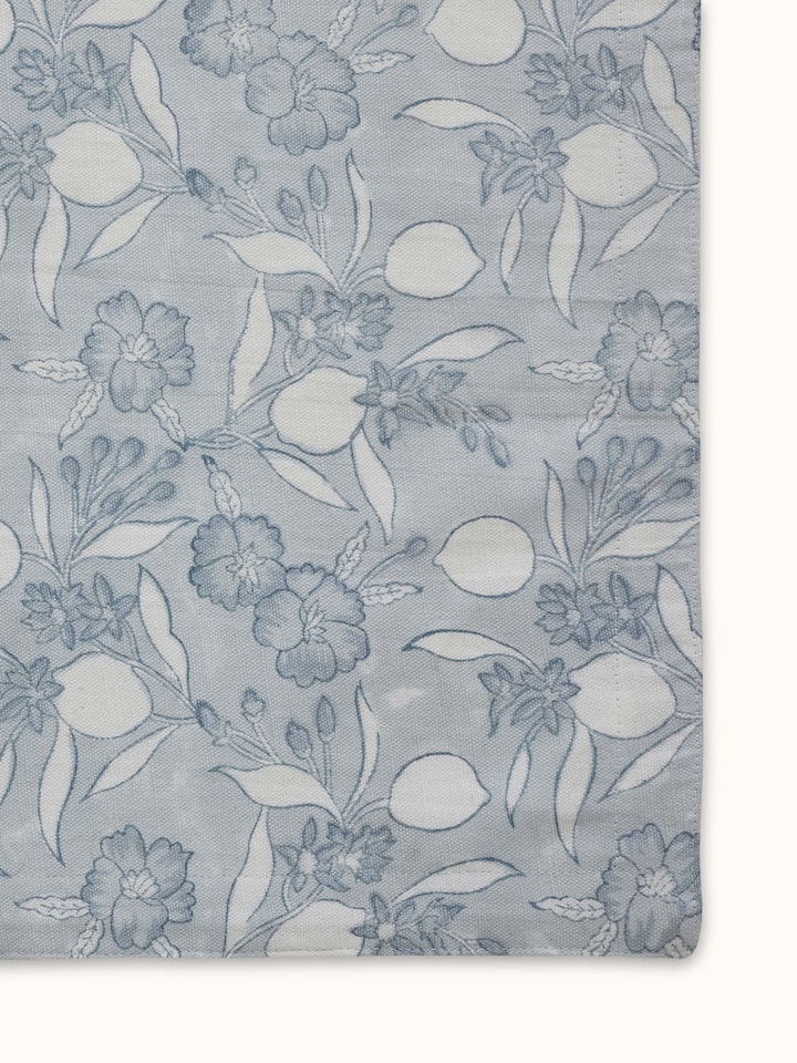 Perspective view of Anika light blue floral cotton Sanganeri block printed apron showing the full apron and block print design.