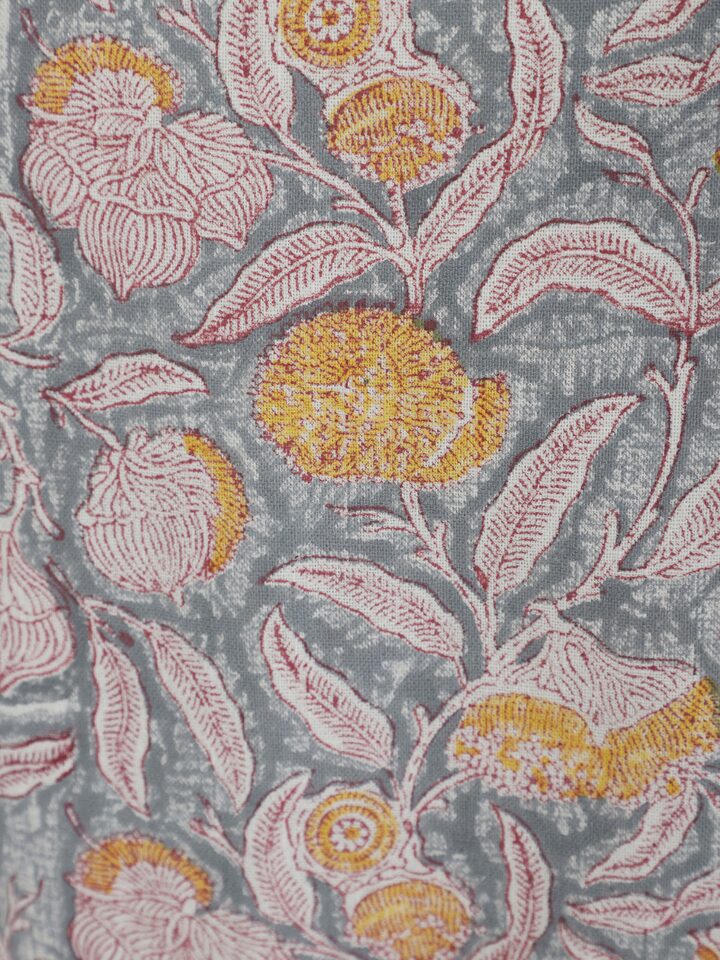 Folded view of grey floral cotton Sanganeri block printed apron showing the overall floral print and cotton material.