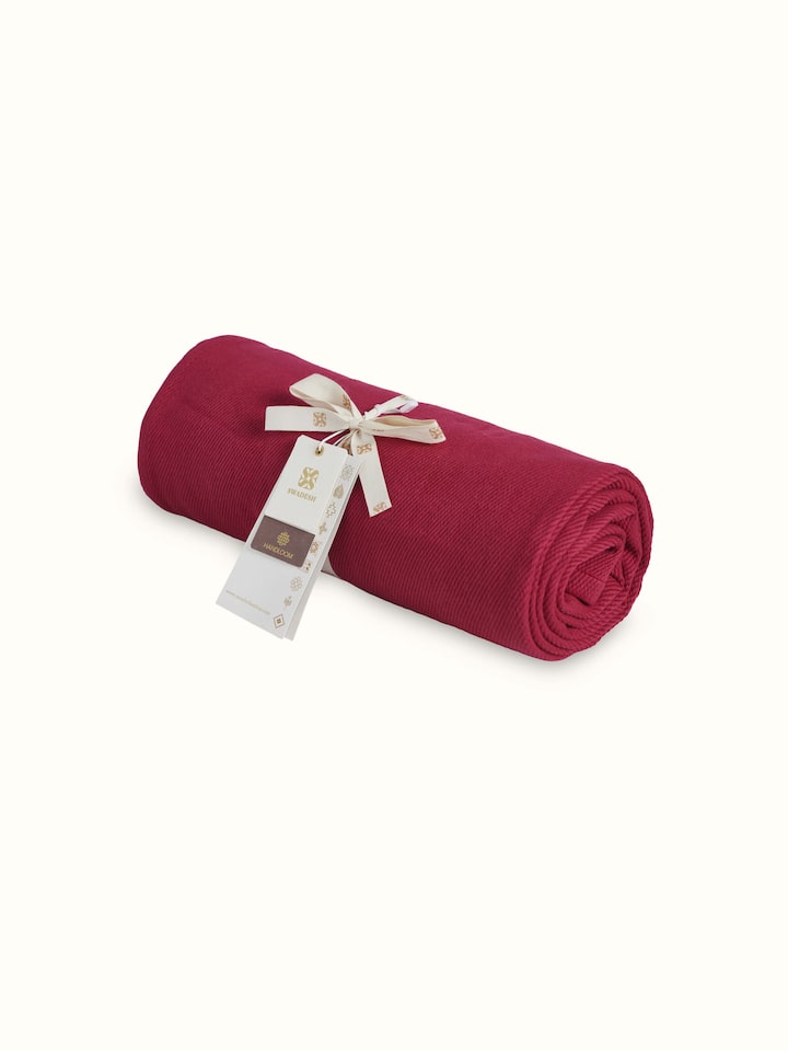 Tavas Magenta handloom throw draped over a surface, showing its texture and design