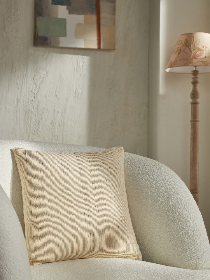 Light brown silk cushion styled on a neutral-toned sofa setup