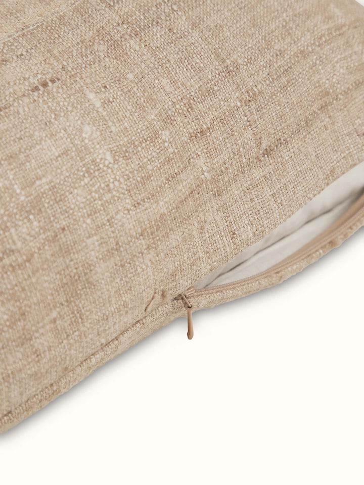 Angled view of Ujjal light brown dharana silk slub handloom cushion cover showing the fine details of the fabric and craftsmanship