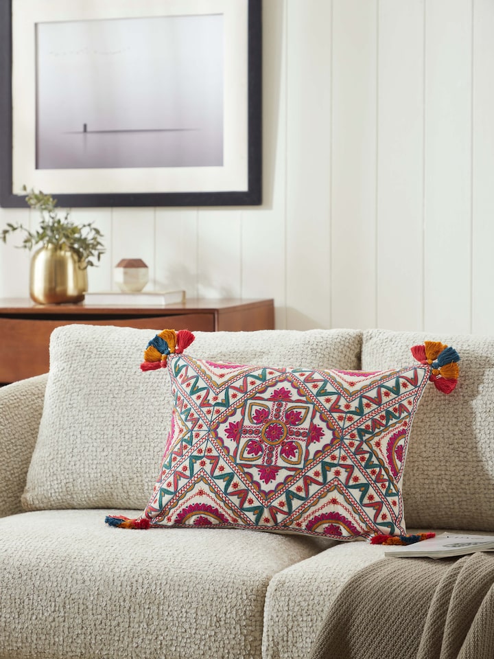 Lifestyle shot of embroidered cushion styled on a neutral background for a vibrant accent.