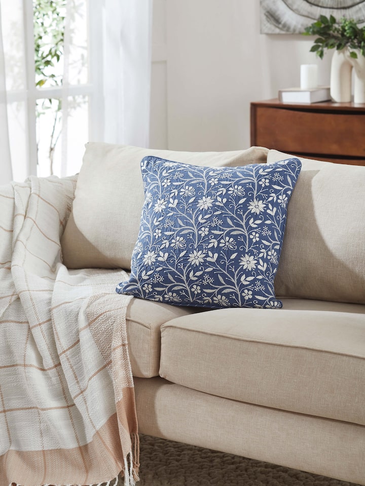 Lifestyle shot of blue Chikankari cushion styled in a cozy setting, showcasing delicate jaal pattern.