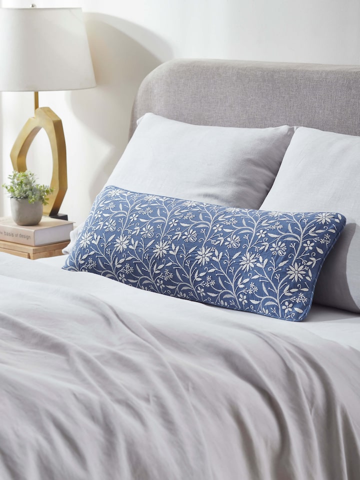 Lifestyle view of Rann hand-embroidered lumbar cushion cover placed on a sofa.