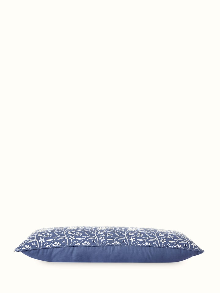 Angled view showing floral Jaal embroidery and blue cotton fabric of cushion cover.