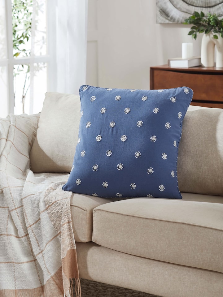 Lifestyle shot showing Rann blue hand embroidered Chikankari cushion cover on a white couch.