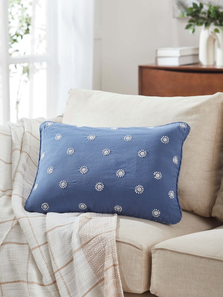Lifestyle shot of blue Chikankari lumbar cushion placed in a styled seating area.