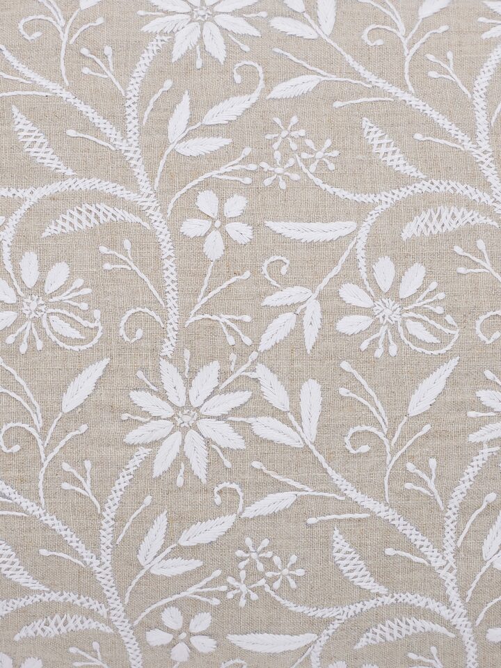 Perspective view of Rann beige allover cotton Chikankari hand embroidered cushion cover showing its elegant embroidery and beige cotton fabric.