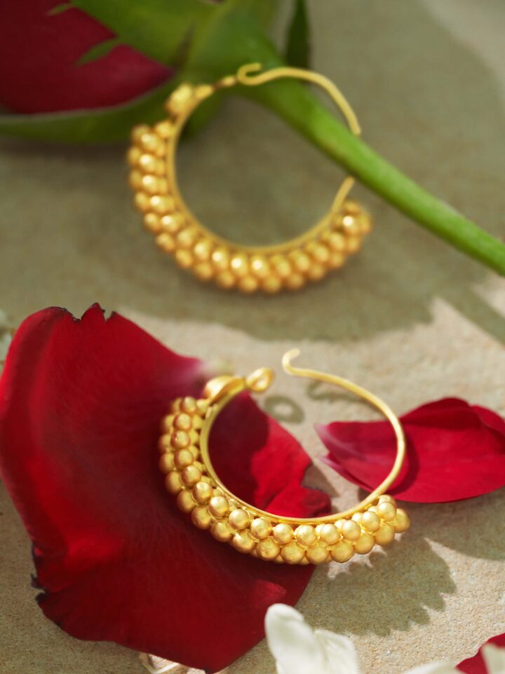 Overhead view of gold hoop earrings with symmetrical round shape and embossed pattern