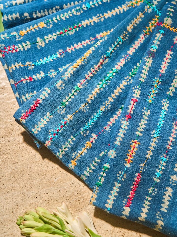 Close-up view of colorful thread embroidery and embellishments on blouse piece