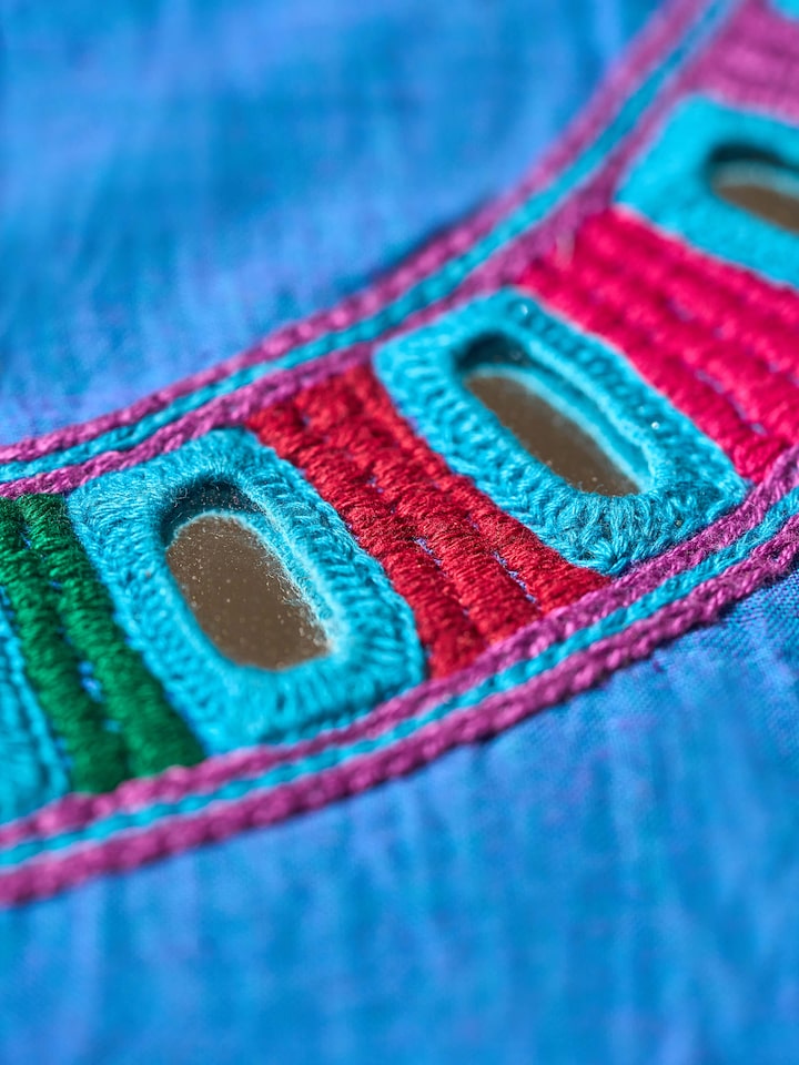 Detail shot of Lambani embroidery on solid blue cotton blouse piece, highlighting intricate stitches