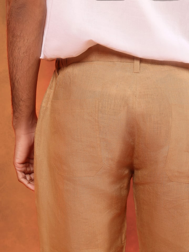 Angled view showing beige linen lounge pant's side seam and soft natural drape