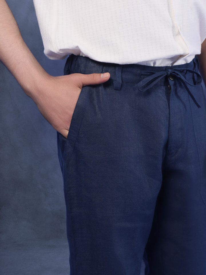 Angled view of navy blue linen elasticated pant highlighting waistband, pleats, and fall of the fabric.