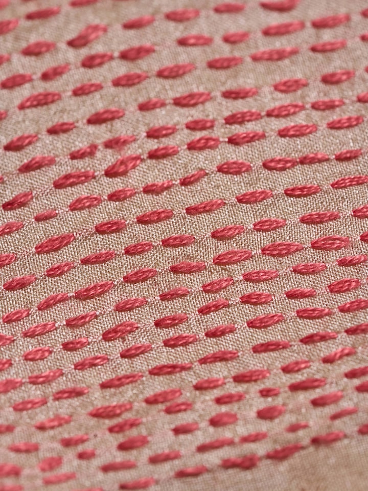 Detailed shot of the embroidery work on off-white tussar silk blouse piece highlighting craftsmanship.